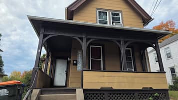 Une maison à deux étages avec un porche, une porte d’entrée et une boîte aux lettres.