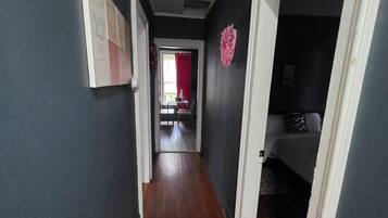A hallway with a wooden floor, a door on the right, and a red curtain in the background.