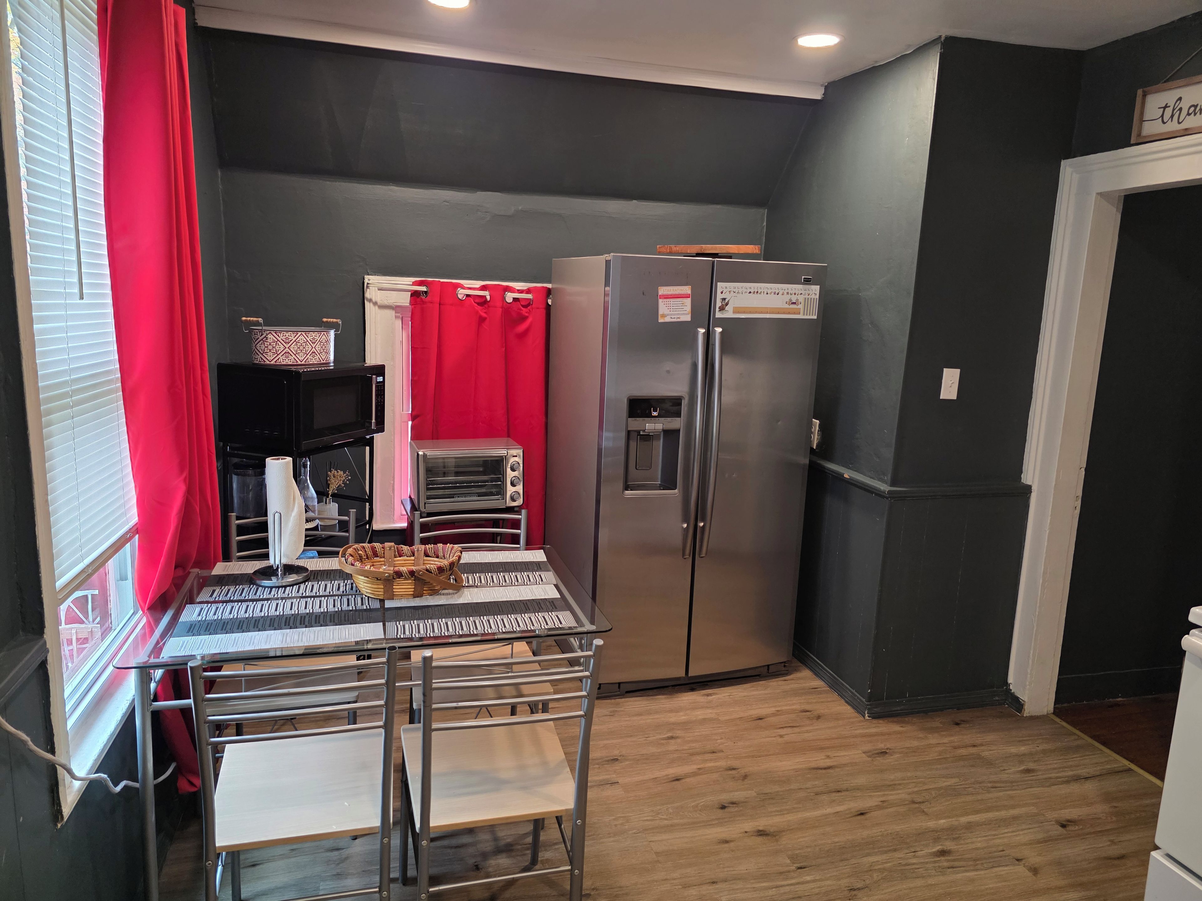 Une cuisine compacte équipée d’un réfrigérateur, d’un grille-pain et d’une table à manger avec des chaises.