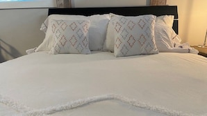 Een opgemaakt bed met wit beddengoed en gestreepte kussens.
