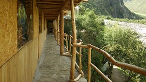 A wooden corridor with a stone floor leading to a mountain view. - Refugios Salkantay (Mollepata)