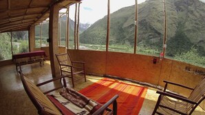 A room with a view of mountains, a wooden bench, and two chairs. - Refugios Salkantay (Mollepata)