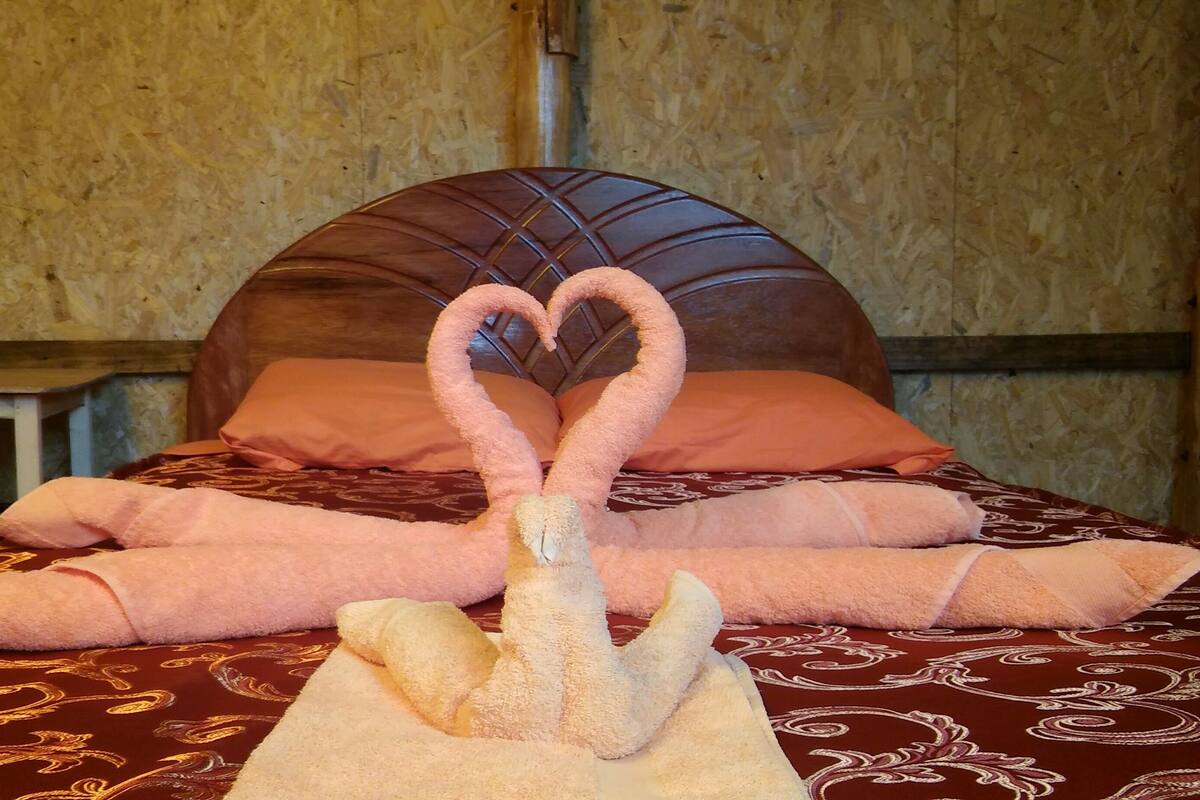 Una cama con una toalla dispuesta en forma de corazón y una escultura de cisne hecha con toallas.