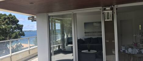 A balcony with a sliding glass door, a sofa, a small table, and a chair.