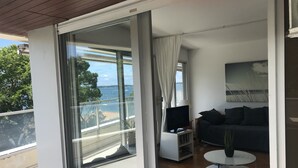 A modern living room with a balcony, a sofa, a coffee table, and a TV. - Arcachon Pereire Appartement Pieds Dans Leau (Arcachon)