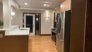 A modern kitchen with wooden cabinets, a stainless steel refrigerator, and a built-in oven.