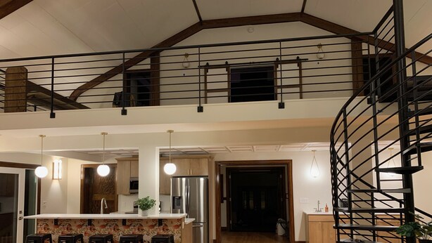 A spacious kitchen with a central island, wooden flooring, and a spiral staircase.