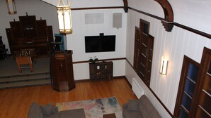 A spacious living room with a large TV, wooden furniture, and a piano.