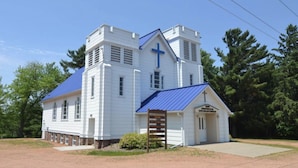 A white church with a blue roof and a cross on the front.
