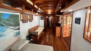 Un interior de madera con una cama, un banco y una pequeña mesa.