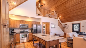 A spacious kitchen with wooden cabinets, stainless steel appliances, and a marble island.
