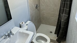 A bathroom with a sink, toilet, and shower. - Budget Inn (Thomasville)