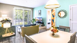 Un salon moderne avec un téléviseur, un canapé, une table à manger et une vue sur l’extérieur.