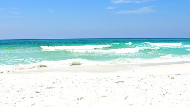 Une plage de sable blanc bordée par des vagues turquoise.