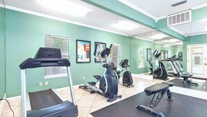 Une salle de sport équipée de tapis de course, d’un appareil elliptique et d’un banc de musculation.