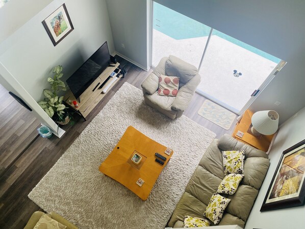 A living room with a sofa, a coffee table, a TV, and a large window.