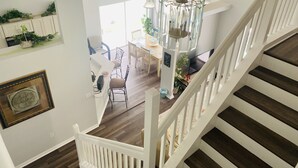 A staircase with white railings leading to a dining area with a chandelier. - Oakchase villa with pool and gameroom sleeps 8 guests easy!  (Davenport)