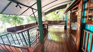 Une terrasse en bois dotée d’un espace abrité, de bancs en bois et offrant une vue sur l’eau.