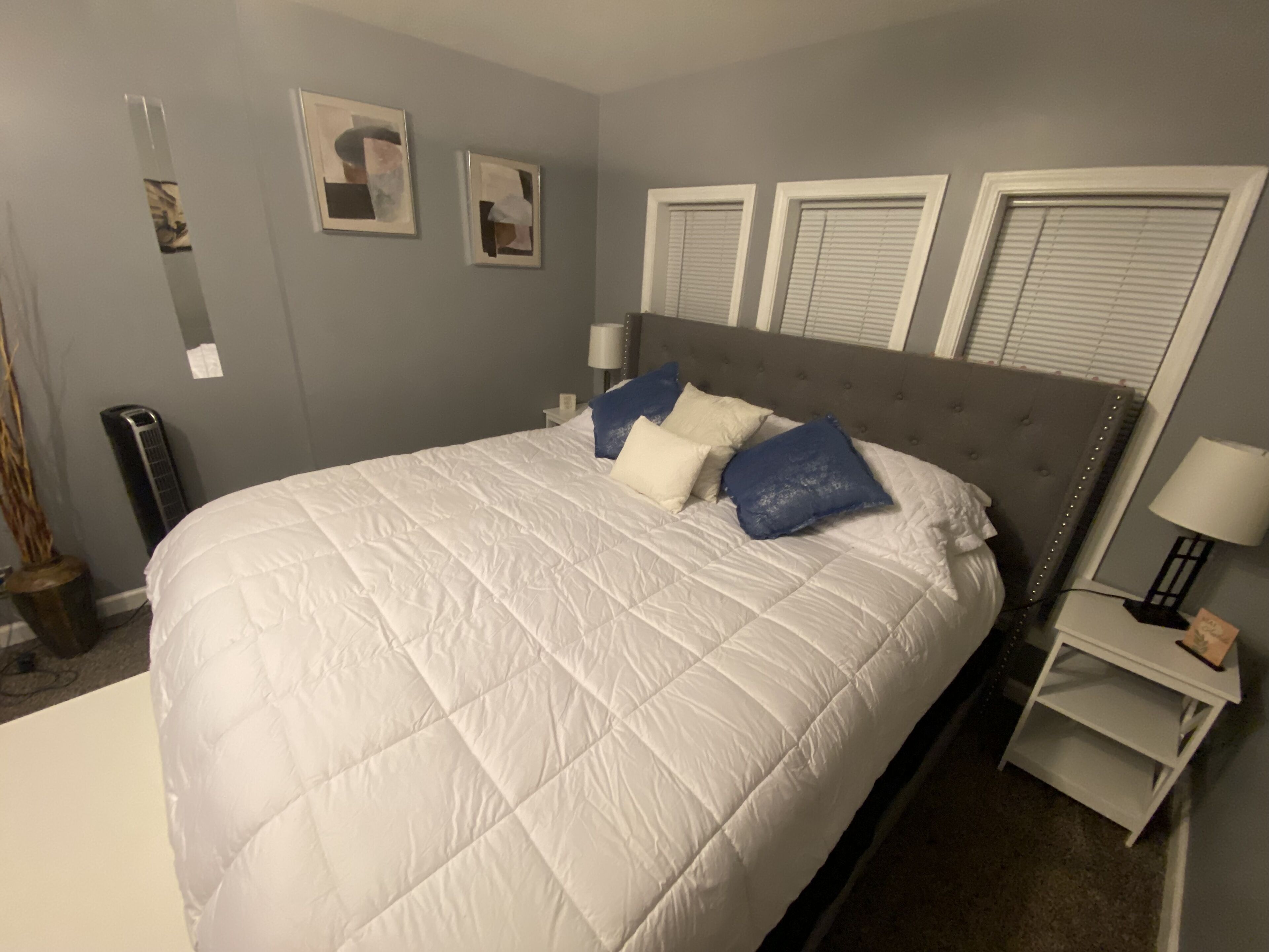 Ein Schlafzimmer mit einem großen Bett, zwei Nachttischen, einer Wandheizung und zwei gerahmten Bildern.