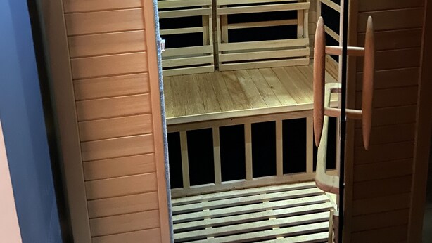 Un sauna doté d’un panneau de commande, de bancs en bois et d’un plancher à lattes.