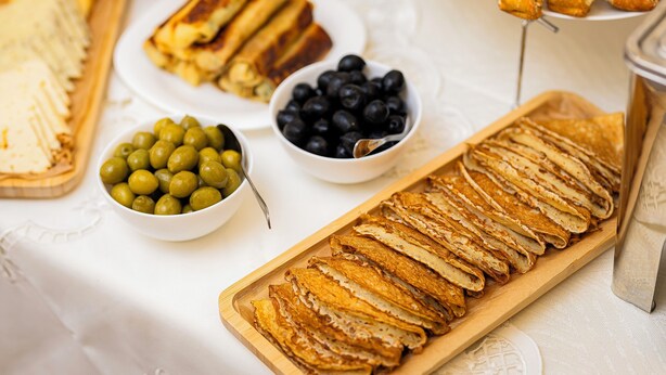 A breakfast buffet with various food items including pancakes, a bowl of olives, and a tray of crepes. - Taniqinn Dilijan Hotel (Dilijan)