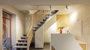 A modern interior with a staircase, a reception desk, and a wooden accent wall. - Taniqinn Dilijan Hotel (Dilijan)