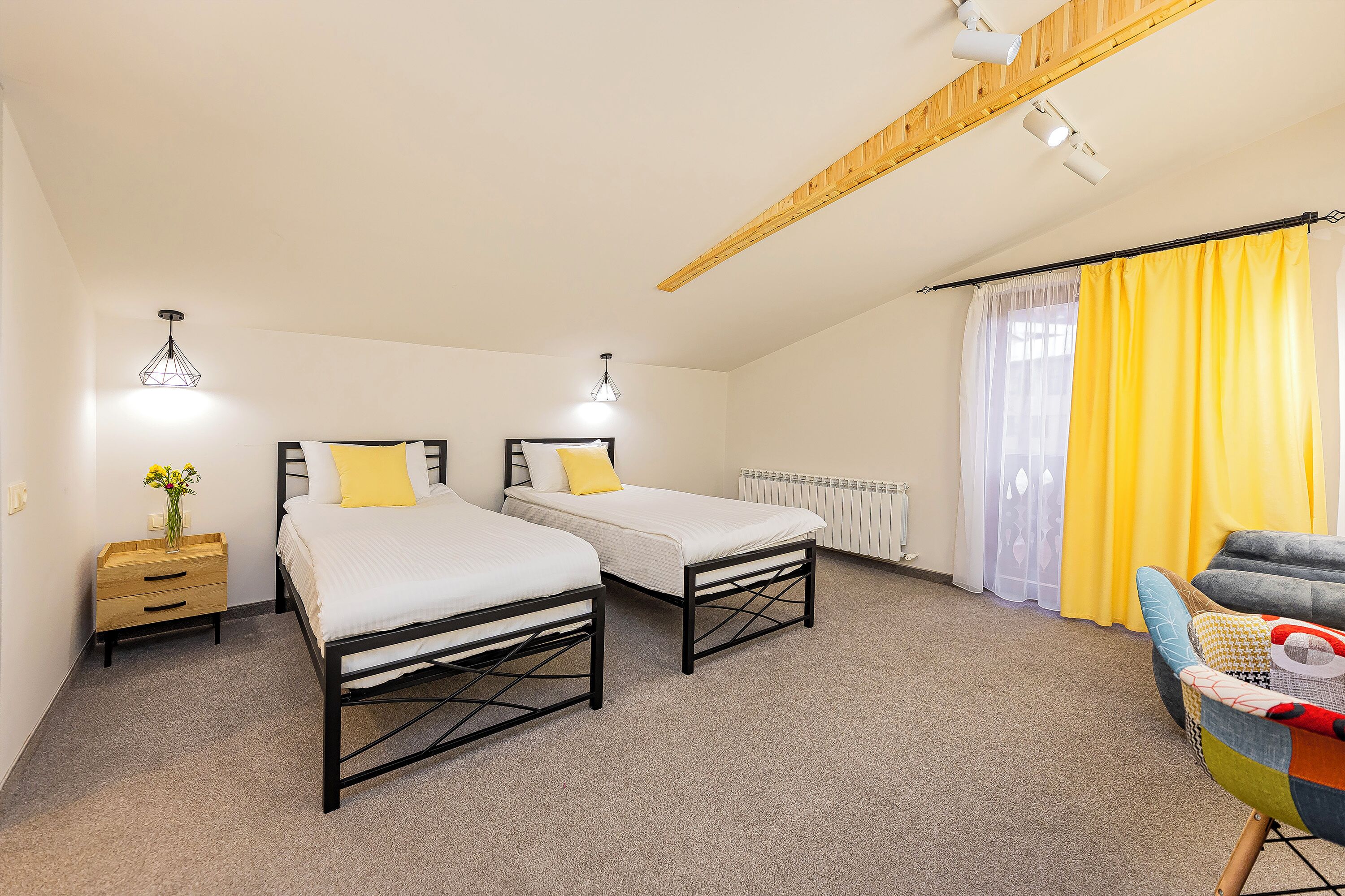 Une chambre avec deux lits, un plafond en bois, un radiateur et une chaise.