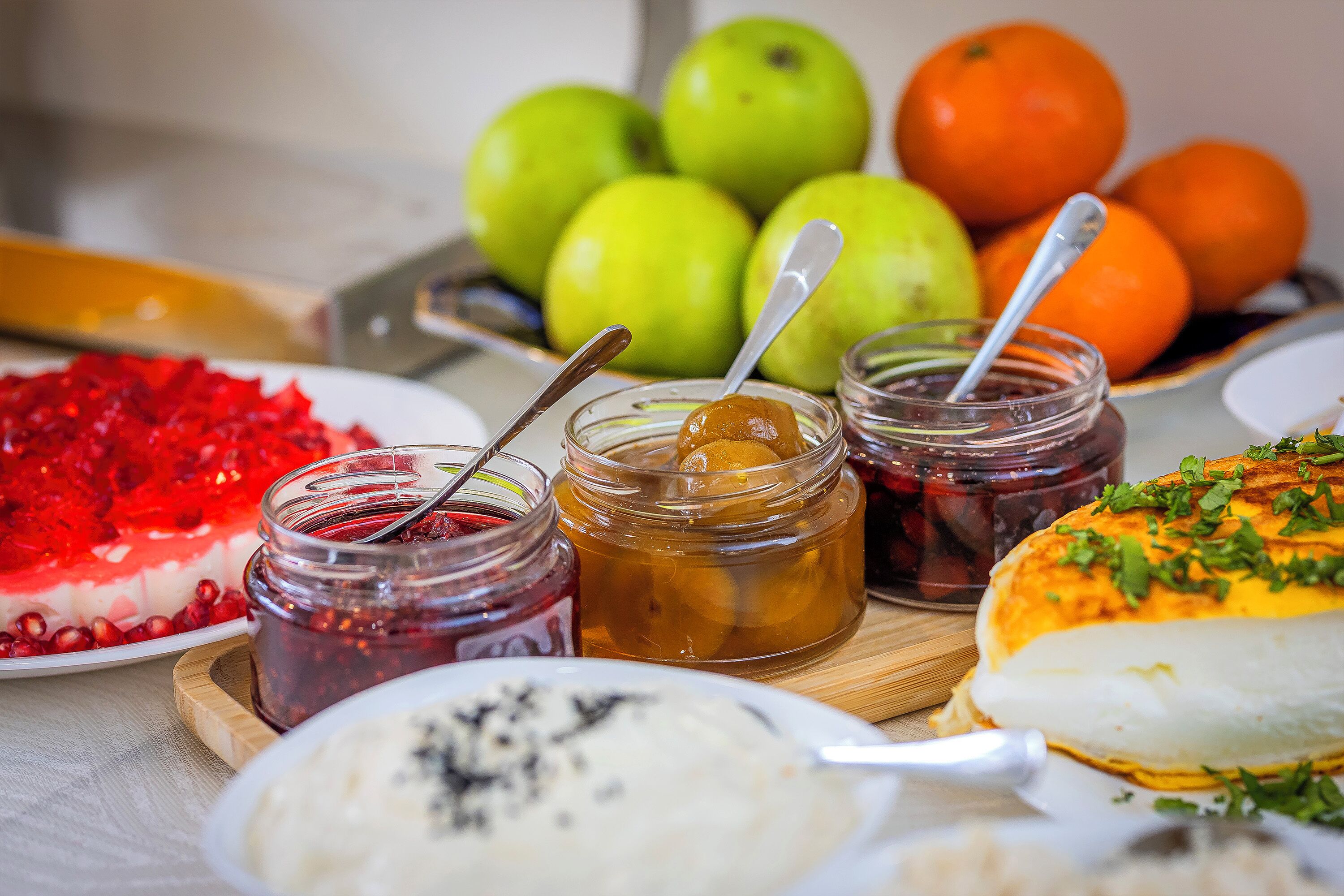 A table with various food items including fruits, jams, and a dessert.