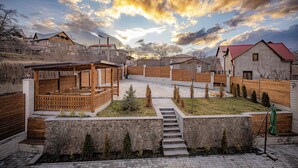 A residential area with a wooden deck, stone walls, and a staircase leading to a covered patio. - Taniqinn Dilijan Hotel (Dilijan)