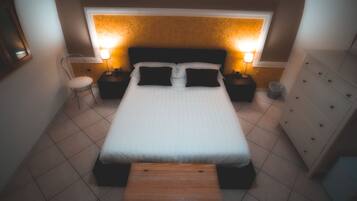 A neatly arranged bedroom with a bed, bedside tables, a chair, and a dresser.
