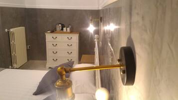 A bathroom with a bed, a white dresser, a radiator, and a shower curtain rod.