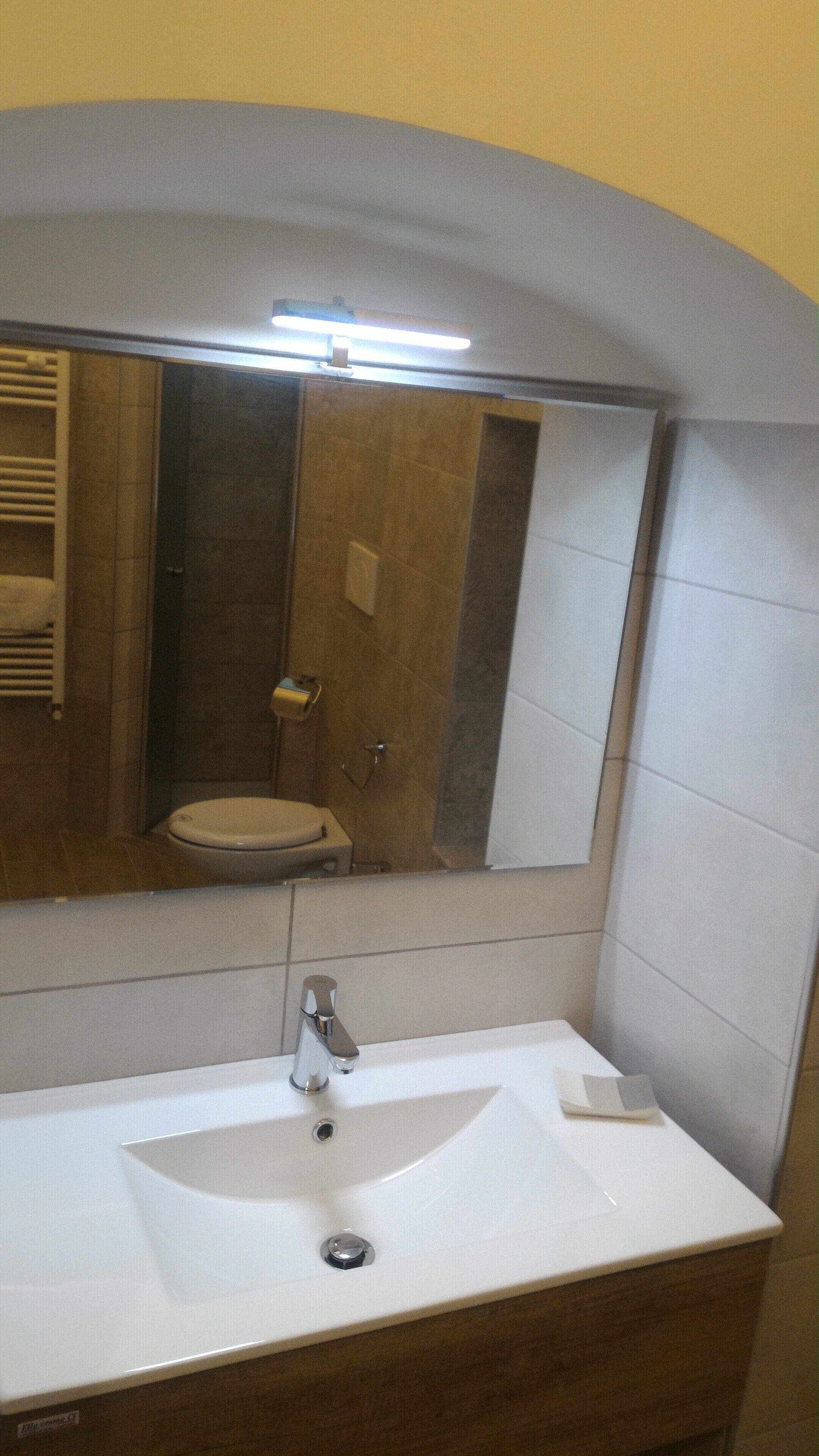 Un baño con lavamanos blanco, un espejo y un inodoro.