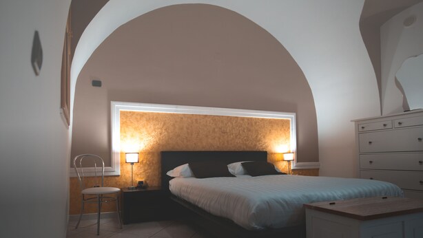 A bedroom with a bed, nightstands, a chair, a dresser, and a window with a view. - IL VICOLO (Ruvo di Puglia)