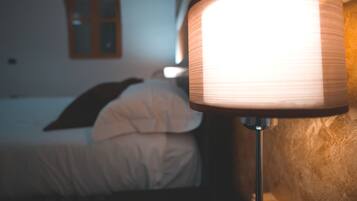 A close-up of a lamp with a ribbed design, positioned next to a bed in a room with a window and a wooden headboard.