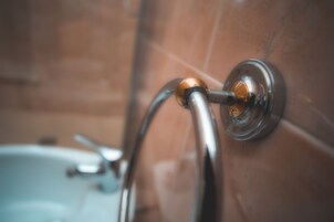 Primer plano de una instalación de baño, probablemente una ducha o grifo, con acabado metálico y base circular.