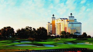 Un campo de golf con un elemento acuático y un hotel al fondo.