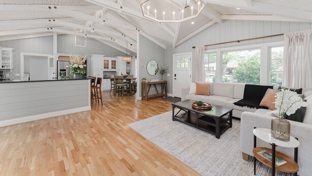 A spacious living area with a large sofa, coffee table, and a dining area with wooden chairs. - Luxury Riverfront Escape- Hot tub & Fire Pit (Roseburg)