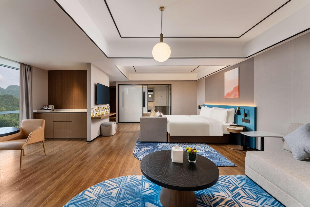 Una habitación de hotel moderna con cama, sofá, escritorio y vistas al exterior.