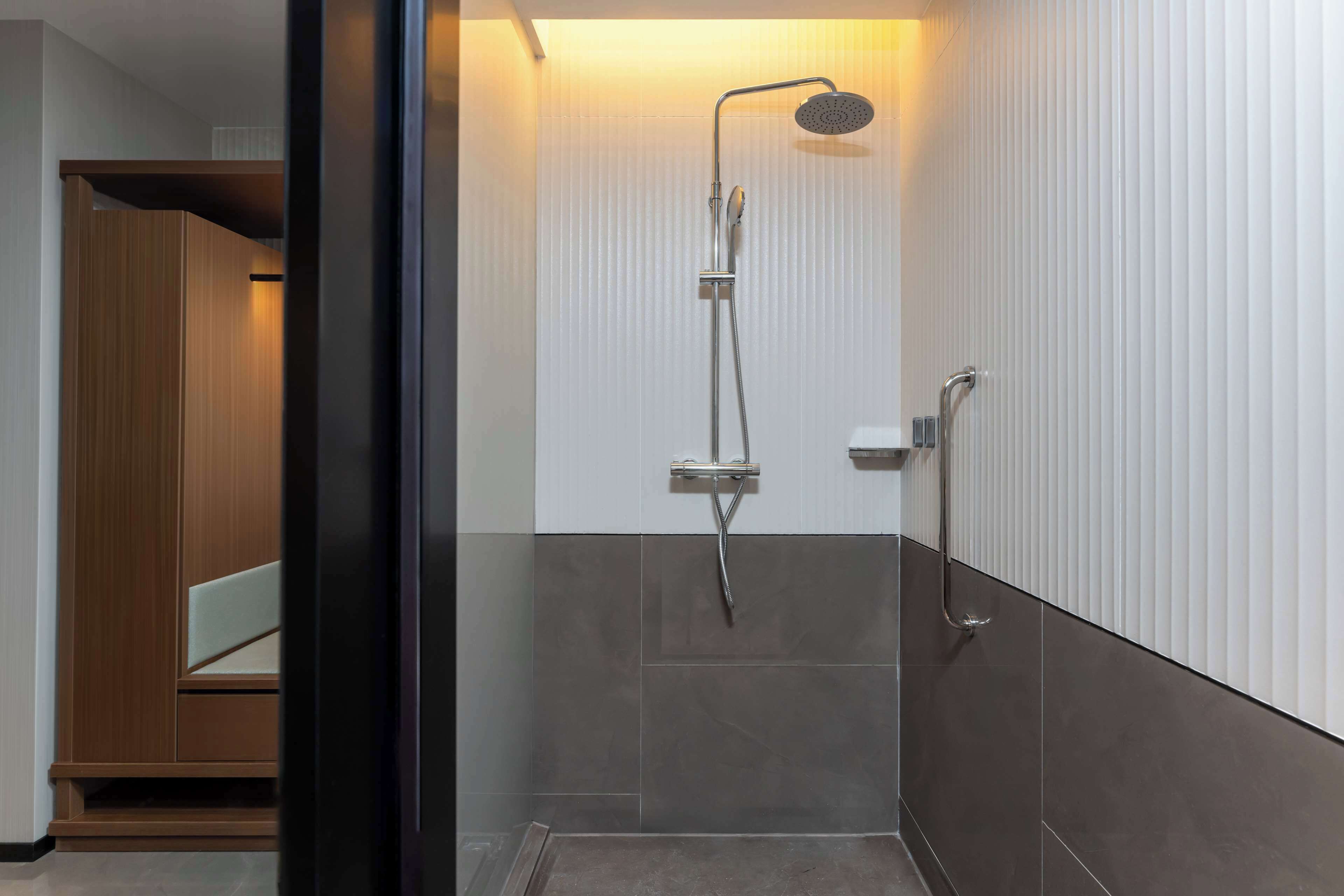 A modern shower with a handheld showerhead and a wall-mounted faucet.