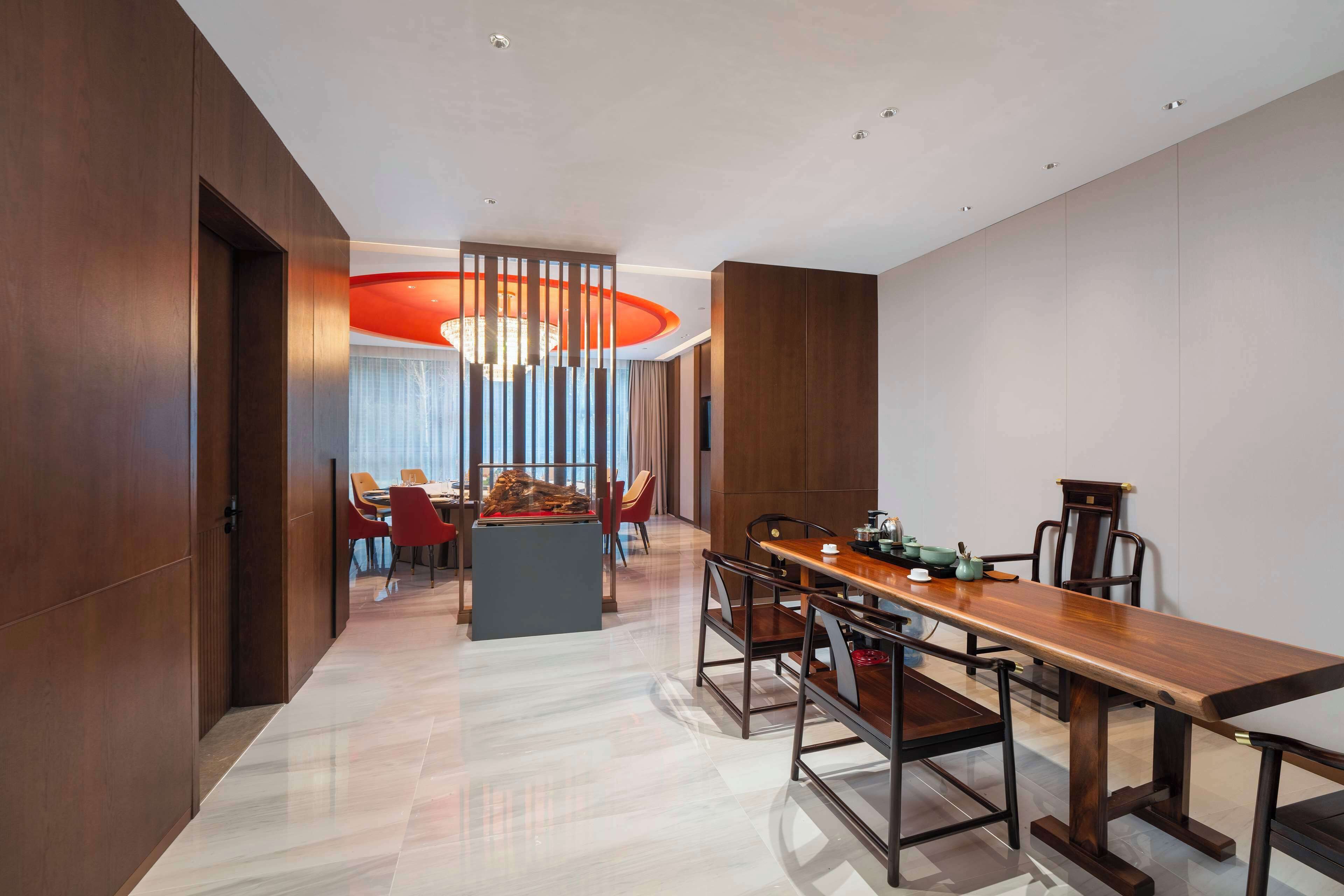 Un comedor moderno con una mesa de madera alargada, sillas rojas y una isla central.