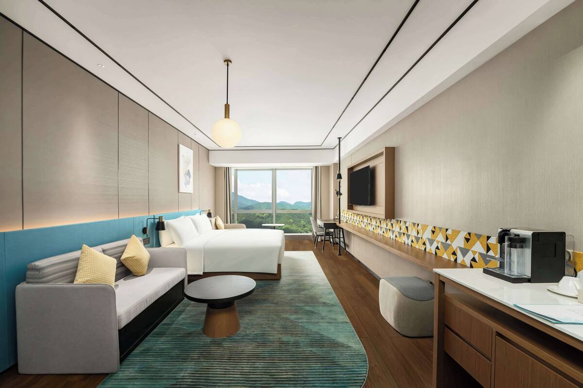 Una habitación de hotel moderna con una cama grande, un sofá, un comedor y vistas a la montaña.
