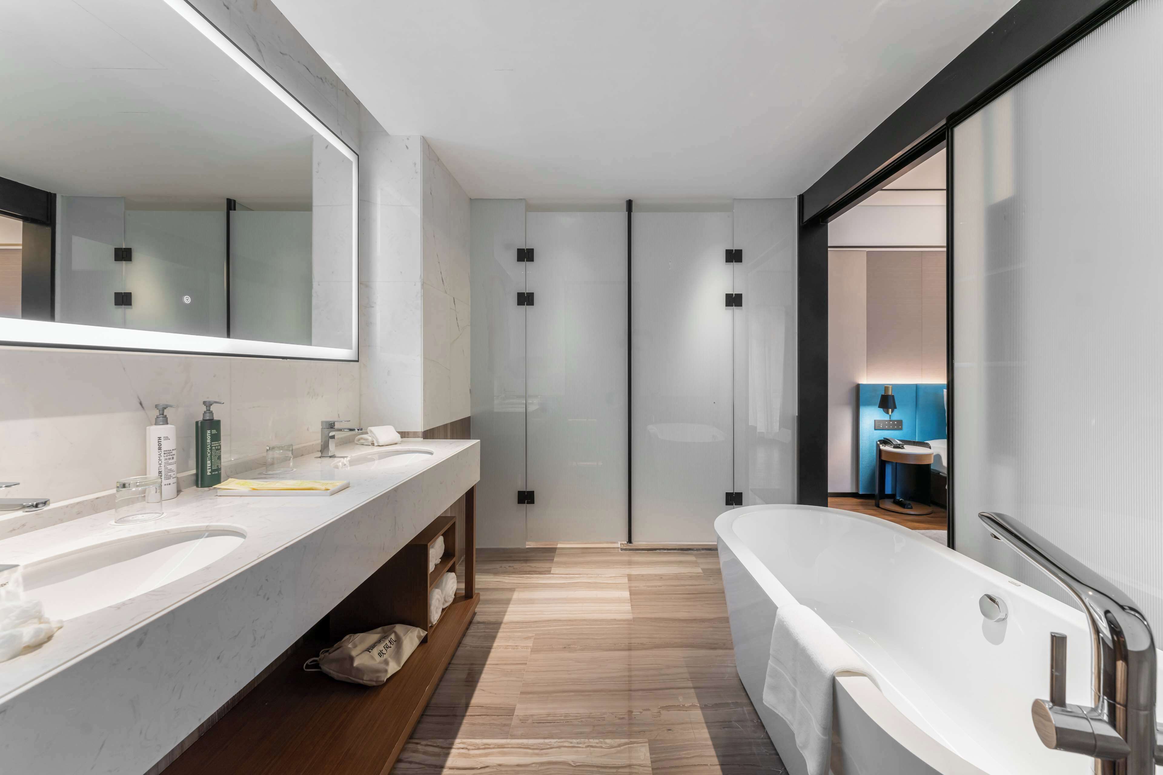 A modern bathroom with two sinks, a large bathtub, and a mirror.