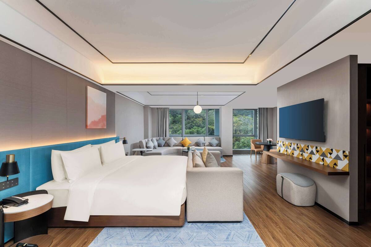 Una habitación de hotel moderna con una cama grande, un sofá, un televisor y un escritorio.