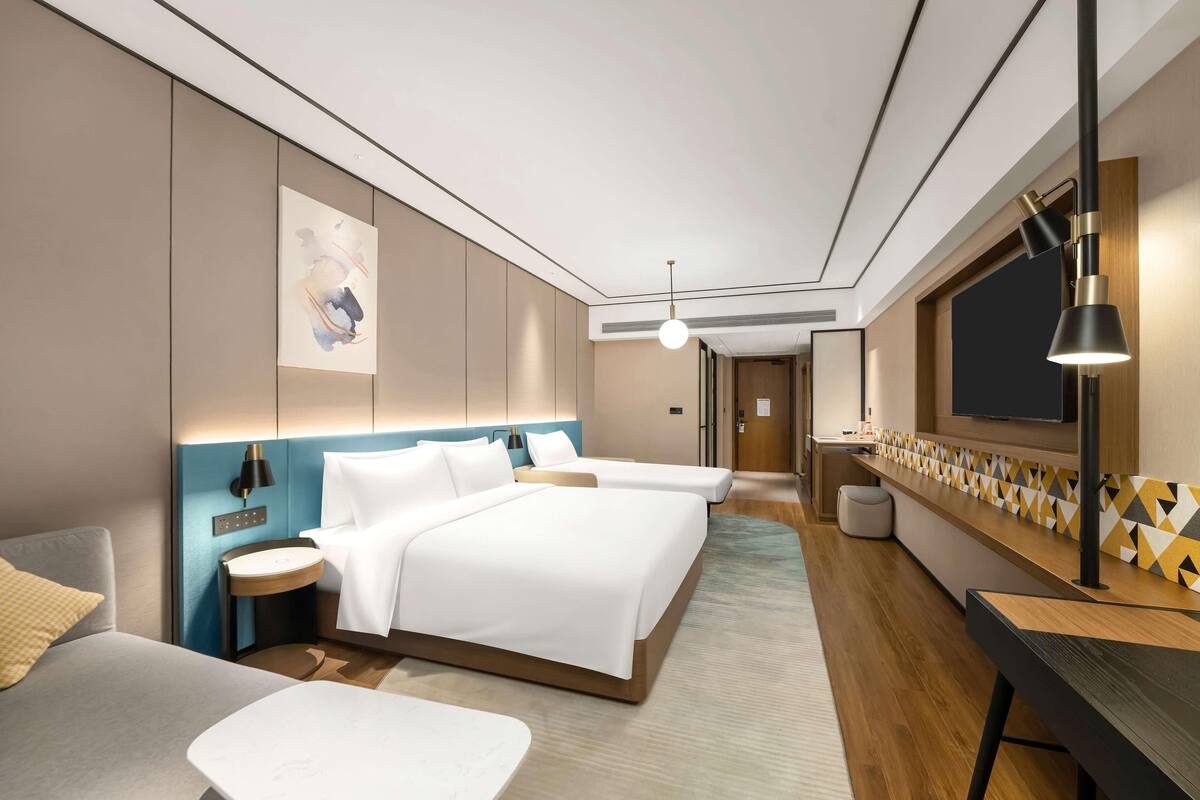 Una habitación de hotel moderna con una cama grande, mesitas de noche, un escritorio y una televisión.