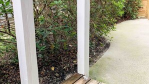 Une terrasse en bois avec un chemin en béton menant à une structure en bois peinte en blanc.