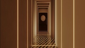 A corridor with a geometric pattern on the floor and walls, leading to a circular door at the end. - Itaim Internacional Stay (São Paulo)