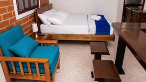 Ett rum med en säng, en blå soffa, ett träbord och ett litet bord.