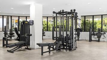 A modern gym with various exercise equipment, large windows, and a clean, spacious layout.