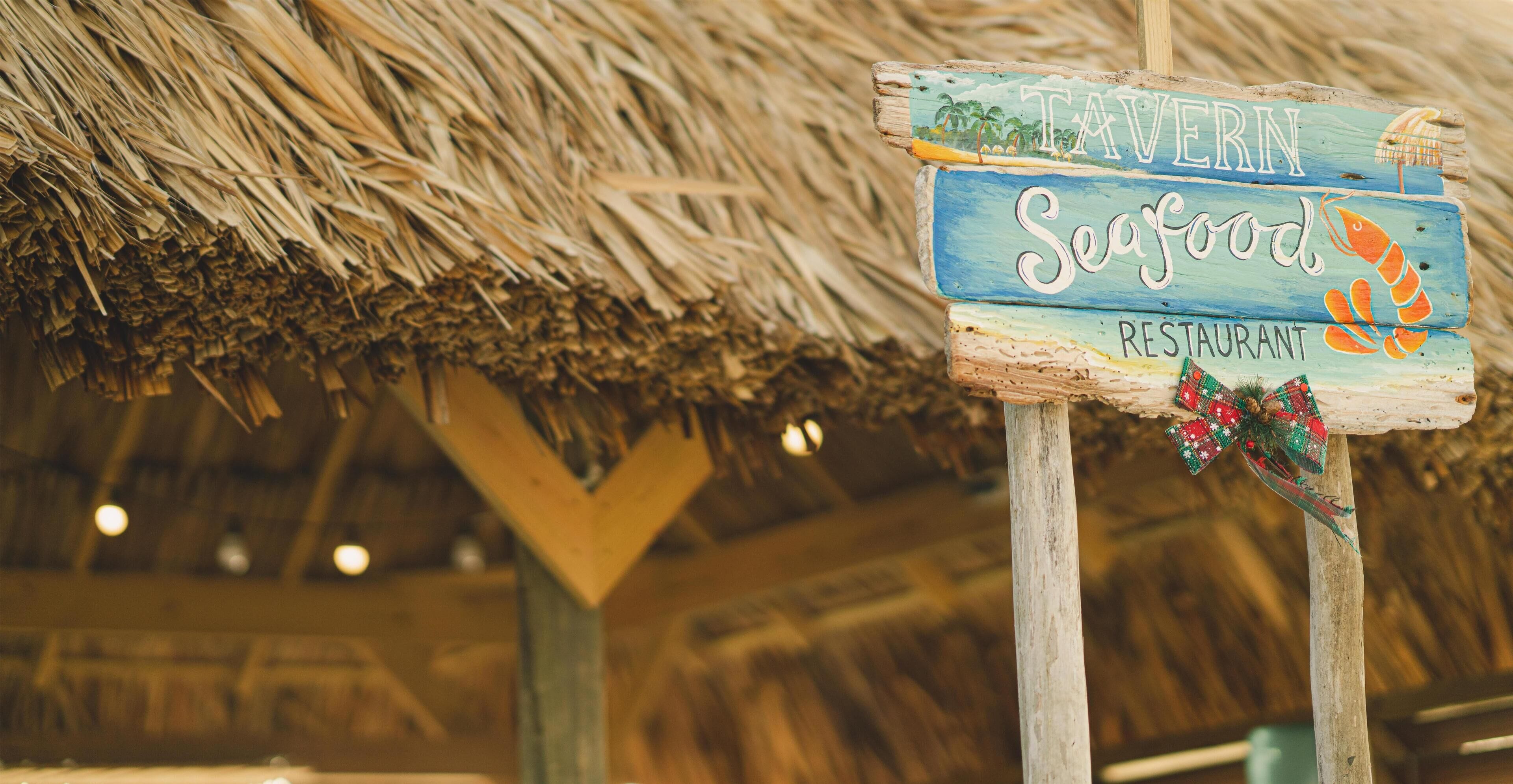 A rustic wooden sign with the text "Tavern Seafood Restaurant" and a lobster graphic.