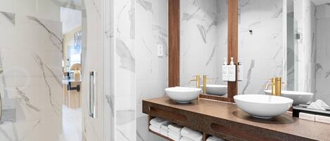 A modern bathroom with marble walls, two sinks, and a large mirror.